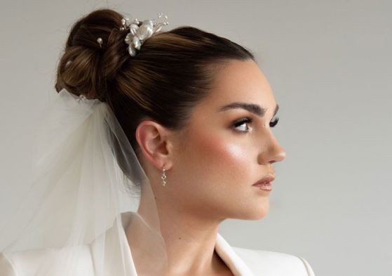 Bride with sleek updo looking to the right with veil on and white suit jacket